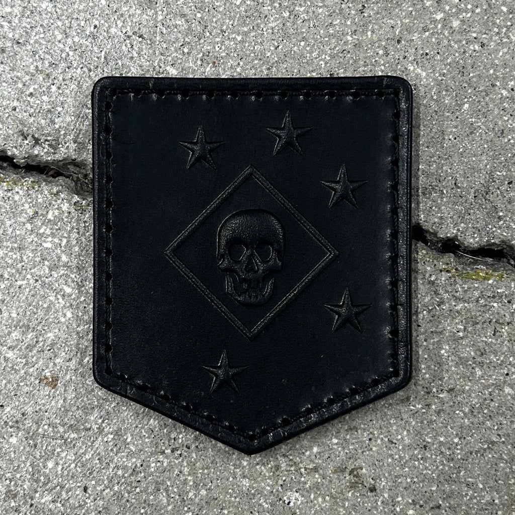 Black leather patch with skull design on a concrete surface