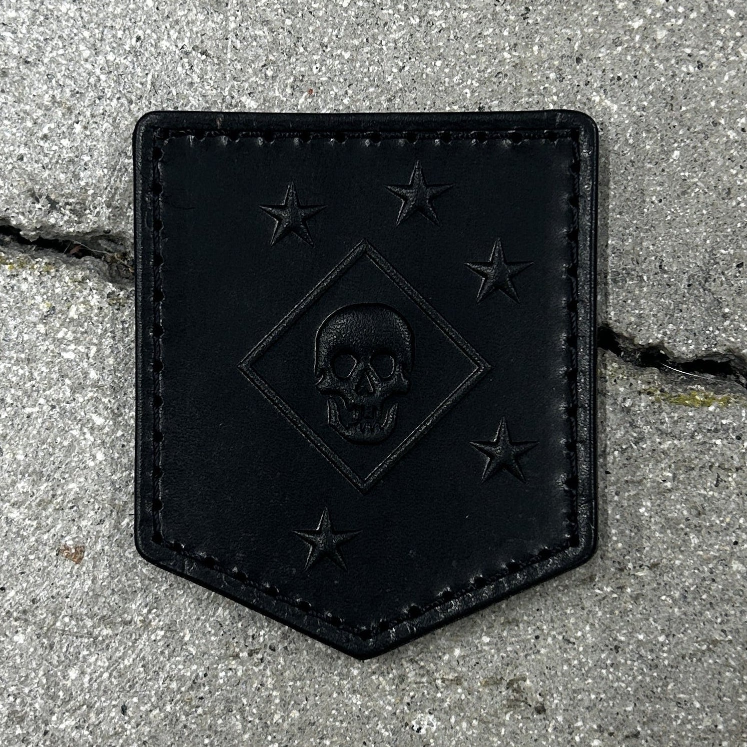 Black leather patch with skull design on a concrete surface