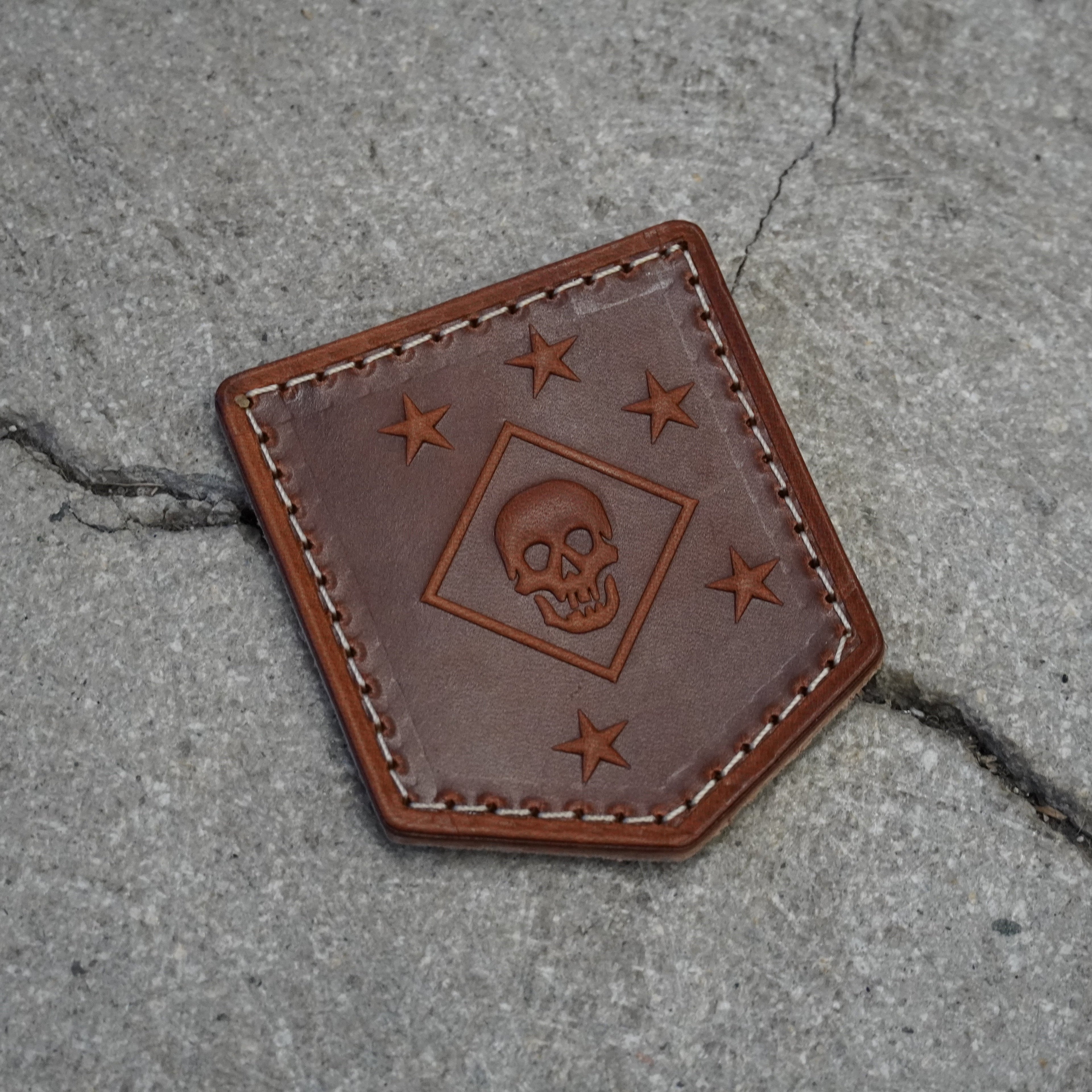 Brown leather patch with marsoc Raider skull design on a concrete surface