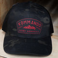 Black camouflage cap with red logo on a wooden surface